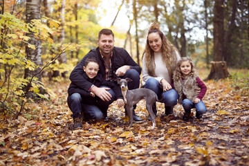 Family of four enjoying golden leaves in autumn park