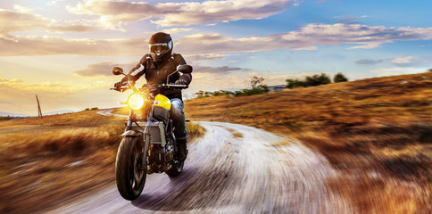 Motorrad fährt auf freier Landstrasse in den Sonnenuntergang
