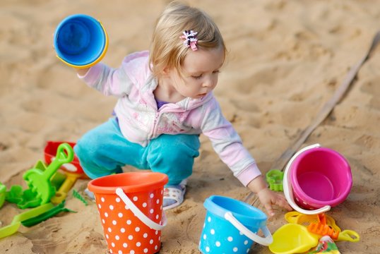 Adorable little girl playing with sand