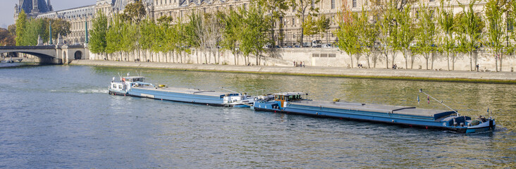 Double péniche sur la seine à Paris devant le Louvre