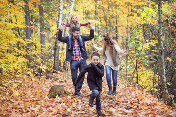 Family of four enjoying golden leaves in autumn park