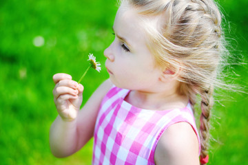 Adorable little girl with daisy on sunny summer day