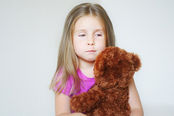 Little sad girl hugging a teddy bear