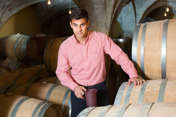 Positive male owner of winery standing with wine