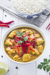 Chicken curry, with onions and chilli on the white table, vertical view, from above
