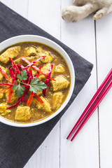 Chicken curry, with onions and chilli on the white table, vertical view, from above