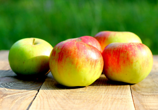 Ripe natural organic brights apples on wooden and green blurred background with copyspace for you text or logo.