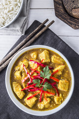 Chicken curry, with onions and chilli on the white table, vertical view, from above