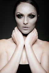 Fashion portrait of a beautiful woman in a black veil on her face. Isolated on gray background. Advertising Space