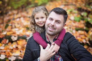 Little adorable girl with happy father in autumn park outdoors