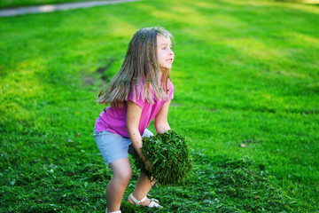 Naklejka na ściany i meble Adorable girl playing with cutted grass