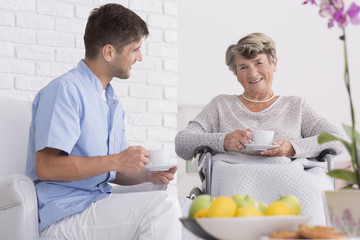 Elder woman on a wheelchair with cup of tea