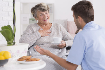 Smiled elder woman and her young male nurse