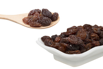 raisins in saucer and raisins in spoon on white background.