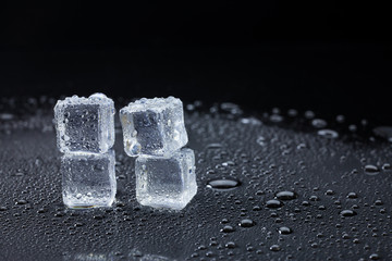 Wet ice cubes and water drop on black background.