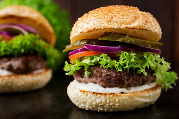 Big sandwich - hamburger burger with beef, pickles, tomato and tartar sauce on black background.