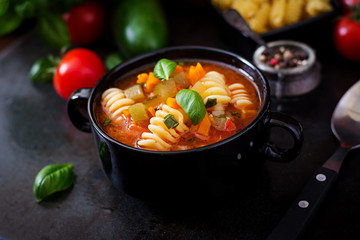 Minestrone, italian vegetable soup with pasta on black backgrounds.