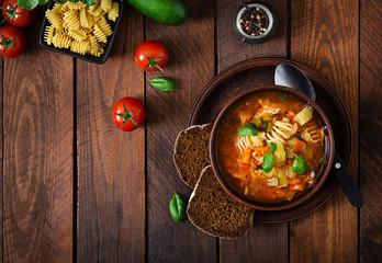 Minestrone, italian vegetable soup with pasta on wooden table. Top view - obrazy, fototapety, plakaty