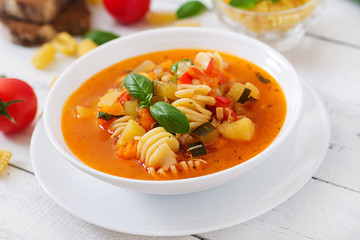 Minestrone, italian vegetable soup with pasta on white wooden table