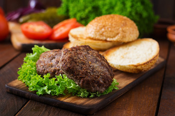 Ingredients for a sandwich - hamburger burger with beef, pickles, tomato and red onion on wooden background.