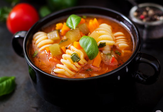 Minestrone, italian vegetable soup with pasta on black backgrounds.