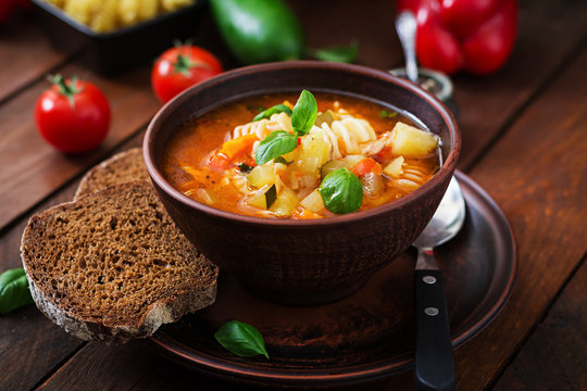 Minestrone, italian vegetable soup with pasta on wooden table