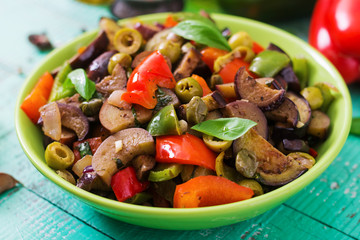 Hot spicy stew eggplant, sweet pepper, olives and capers with basil leaves.