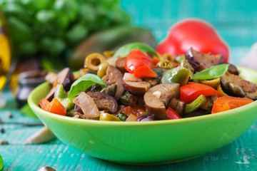 Hot spicy stew eggplant, sweet pepper, olives and capers with basil leaves.