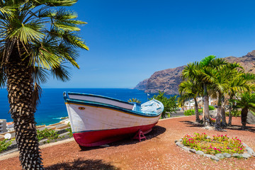 A colourful painted fishing boat on display near the ocean in Los Gigantes, Tenerife, Canary Islands, a picture postcard scenic view of the island. © daliu