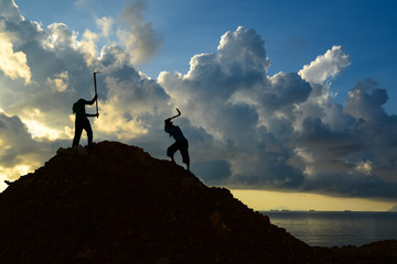 Workers using hoe to dig heap of soil