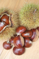 Castagne e ricci su tavolo di legno