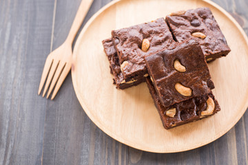Chocolate brownie with cashew nuts on wooden background.
