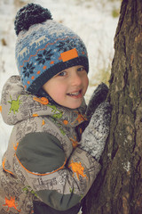 Smiling boy in the winter pine forest