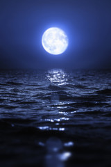 Fototapeta na wymiar Full moon rising over empty ocean at night