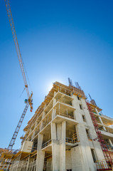 Fototapeta na wymiar High-rise building under construction. The site with cranes against blue sky