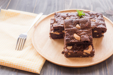 Chocolate brownie with cashew nuts on wooden background.