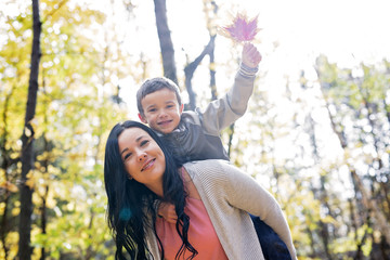 Adorable little boy with his mother in autumn park