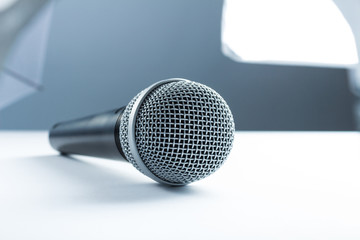 A microphone lying on a white table. Against the background of studio equipment, lighting.