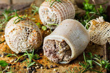 Pork rolls with spices and seasoning on old cutting board