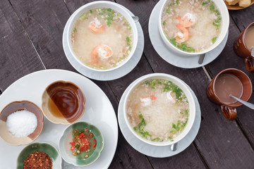 Thai rice soup with shrimp and pork, seasoning, fish sauce, pickled chilli, cayenne pepper, sugar on wood table