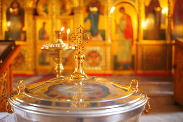 The font for the baptism of children in the Orthodox Church. Symbolic Orthodox gold cross on the cover font.
