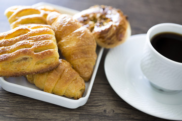 Croissants with coffee on the wooden table. Office workplace