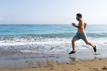 Fototapeta premium Man runner sprinting on wet sand run at the beach