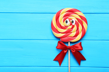 Sweet lollipop with googly eyes on blue wooden table
