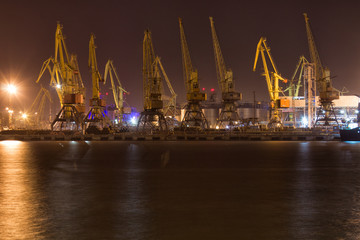 Fototapeta na wymiar Cargo cranes and loading / discharging terminal of port Odessa, Ukraine. Night view picture