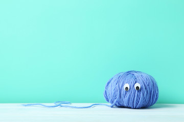 Ball of yarn with googly eyes on a green background