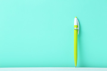 Pen with googly eyes on a green background