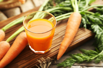 Fresh carrot juice in glass on a grey wooden table