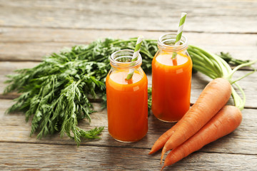 Fresh carrot juice in bottles on a grey wooden table