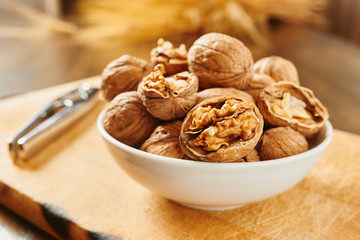 Walnuts in bowl and nutcracker on a cutting board and wooden table